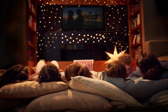 Kids sitting on lawn watching a movie on a big screen